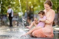 Portrait of beautiful disabled girl in the arms of his mother having fun in fountain of public park at sunny summer day. Child Royalty Free Stock Photo