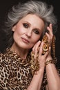 Portrait of a beautiful elderly woman in a leopard blouse with classic makeup and gray hair.