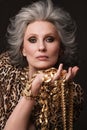 Portrait of a beautiful elderly woman in a leopard blouse with classic makeup and gray hair.