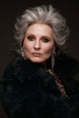 Portrait of a beautiful elderly woman in a leopard blouse and fur coat with classic makeup and gray hair.