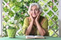 Beautiful elderly woman sits at a table and reading book Royalty Free Stock Photo