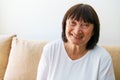 Portrait of a beautiful elderly woman smiling while sitting on the sofa at home Royalty Free Stock Photo