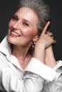 Portrait of a beautiful elderly woman in a white shirt with classic makeup and gray hair.