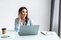 Portrait of beautiful executive woman making call while sitting at her workplace in front of laptop and working on new project Royalty Free Stock Photo
