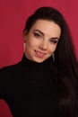 Portrait of a beautiful fashion glamour girl brunette in black clothes in the studio with big earrings on the pink background Royalty Free Stock Photo