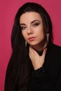 Portrait of a beautiful fashion glamour girl brunette in black clothes in the studio with big earrings on the pink background Royalty Free Stock Photo