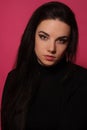 Portrait of a beautiful fashion glamour girl brunette in black clothes in the studio with big earrings on the pink background Royalty Free Stock Photo