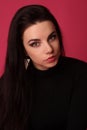 Portrait of a beautiful fashion glamour girl brunette in black clothes in the studio with big earrings on the pink background Royalty Free Stock Photo