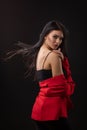 Portrait of a beautiful fashionable brunette woman in a red business suit on black background Royalty Free Stock Photo