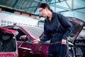 Portrait of beautiful female auto mechanic in uniform welding car body panel, auto mechanic technician woman fixing, repairing