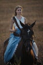 Portrait of a beautiful female cowgirl with shotgun from wild west riding a horse in the outback. Royalty Free Stock Photo