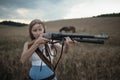 Portrait of a beautiful female cowgirl with shotgun from wild west riding a horse in the outback. Selective focus. Royalty Free Stock Photo