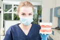 Portrait of beautiful female dentist wearing mask and holding jaws