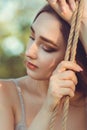 Portrait of beautiful female face near ropes of swing, girl swinging on nature, young pensive romantic woman, solitude, lifestyle Royalty Free Stock Photo