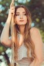 Portrait of beautiful female face near ropes of swing, girl swinging on nature, young pensive romantic woman, solitude, lifestyle Royalty Free Stock Photo