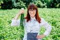 Portrait of a beautiful female farmer holding a fresh bunch of green onions, smiling at the camera and surrounded by plenty of