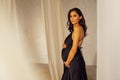 Portrait of beautiful female pregnant in black dress touching her belly. Close up of studio snapshot of young woman expecting baby Royalty Free Stock Photo