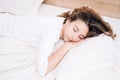 Young woman sleeping in bed. Portrait of beautiful female resting on comfortable bed with pillows In white bedding In light Royalty Free Stock Photo