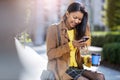 Young woman with smartphone and coffee in the city