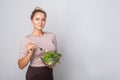 Portrait of beautiful fit woman with hair bun holding bawl of fresh vegetable salad and looking at camera