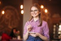 Portrait of a beautiful friendly waitress in glasses with notepapers and pen ready to take your order Royalty Free Stock Photo