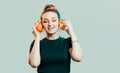 Portrait of beautiful funny girl with orange halves like headphones for listening to music, woman fooling around, concept music of Royalty Free Stock Photo