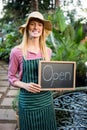 Portrait of beautiful gardener with open text on chalkboard at garden