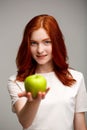 Portrait of beautiful ginger girl holding apple blurred over gray background. Royalty Free Stock Photo