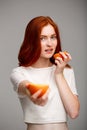 Portrait of beautiful ginger girl holding oranges over gray background. Royalty Free Stock Photo