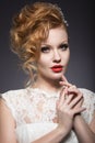 Portrait of a beautiful ginger woman with red lips in the image of the bride.