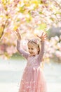 Portrait of beautiful girl with blooming flowers. Cherry blossom. Little caucasian girl with long blonde hair standing in the park Royalty Free Stock Photo