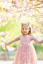 Portrait of beautiful girl with blooming flowers. Cherry blossom. Little caucasian girl with long blonde hair standing in the park Royalty Free Stock Photo