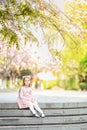 Portrait of beautiful girl with blooming flowers. Cherry blossom. Little caucasian girl with long blonde hair standing in the park Royalty Free Stock Photo