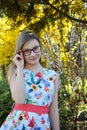 Portrait of beautiful girl with brown hair looking over glasses and surprised. Young smiling teneeger in green spring park resting Royalty Free Stock Photo