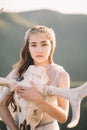 Portrait of beautiful girl brunette bride in white dress is made of tulle, decoration for hair on the head, looks straight lips