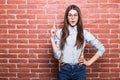 Portrait of beautiful girl in casual clothes showing UP sign, looking in camera Royalty Free Stock Photo