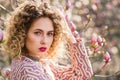 Portrait of beautiful girl with curly long hair in pink blouse walks in garden of magnolias