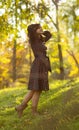 Portrait of a beautiful girl in a dress walking in nature in the fall, a young woman enjoying the sunshine standing on a hill with Royalty Free Stock Photo