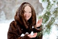 Portrait of a beautiful girl in a fur hood on a Sunny winter day in the Park. The girl looks tenderly at the camera. The Royalty Free Stock Photo