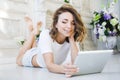 Portrait of a beautiful girl gentle, cute young, lying on the floor, with laptop posing Royalty Free Stock Photo