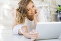 Portrait of a beautiful girl gentle, cute young, lying on the floor, with laptop posing Royalty Free Stock Photo