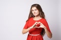 Portrait beautiful girl. Gesture heart. Brunette. Red dress. White background