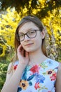 Portrait of beautiful girl with glasses and brown hair. Young smiling teneeger in green spring park resting among grass and Royalty Free Stock Photo