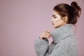 Portrait of beautiful girl in grey sweater posing in profile over pink background. Royalty Free Stock Photo