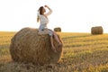 Portrait of beautiful girl on haystack roll on harvested wheat field in the summer. Selective focus