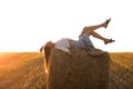 Portrait of beautiful girl on haystack roll on harvested wheat field in the summer. Selective focus