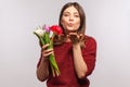 Portrait of beautiful girl holding bouquet of tulips, sending sensual air kiss, expressing love feelings on romantic date Royalty Free Stock Photo