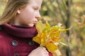 Portrait of a beautiful girl holding a bunch of fallen tree leaves in the autumn forest Royalty Free Stock Photo