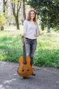 Portrait of a beautiful girl holding her guitar in the park and smiling Royalty Free Stock Photo