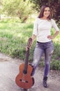 Portrait of a beautiful girl holding her guitar in the park and smiling Royalty Free Stock Photo